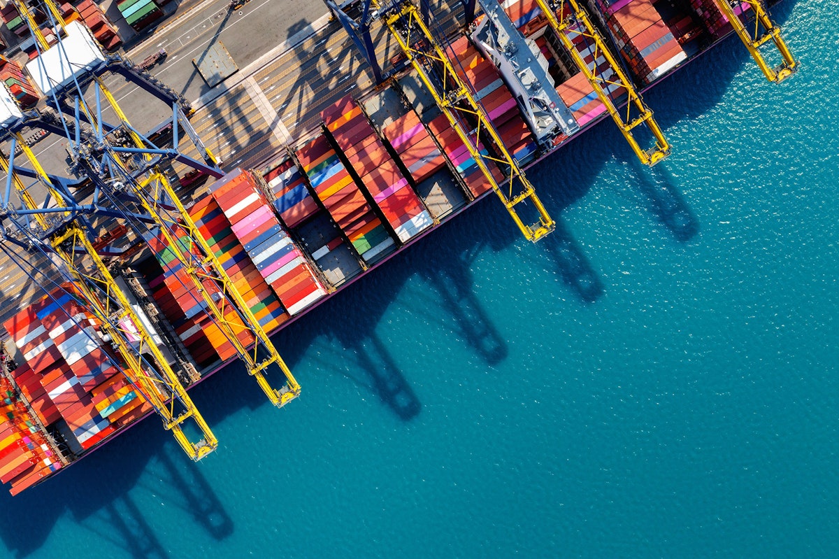 Aerial view of a cargo ship carrying containers in a harbor. 