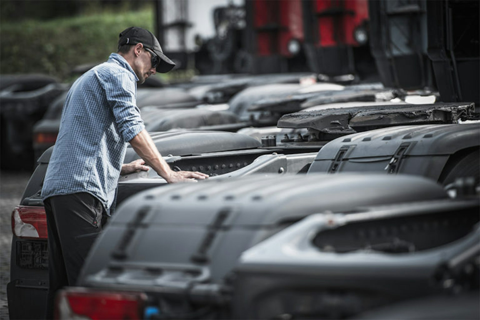 Man looking at a line of semi tractors without trailers. 