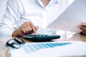 Female banker using a calculator while looking at financial documents.