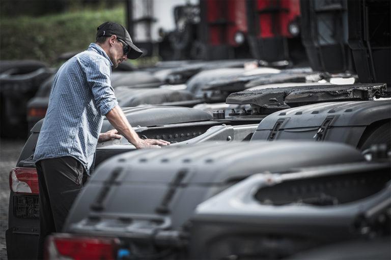 Man looking at a line of semi tractors without trailers.